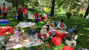 dzieci uczestniczą w zabawach z wolontariuszami PCK na skwerze przed Chatką Żaka