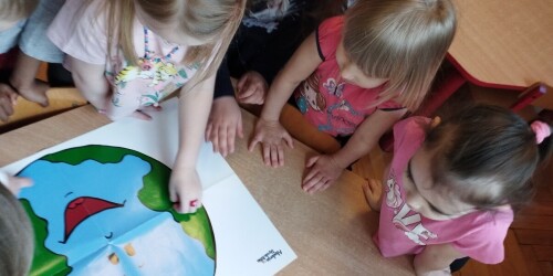 dzieci przy stoliku omawiają plakat z okazji Dnia Ziemi